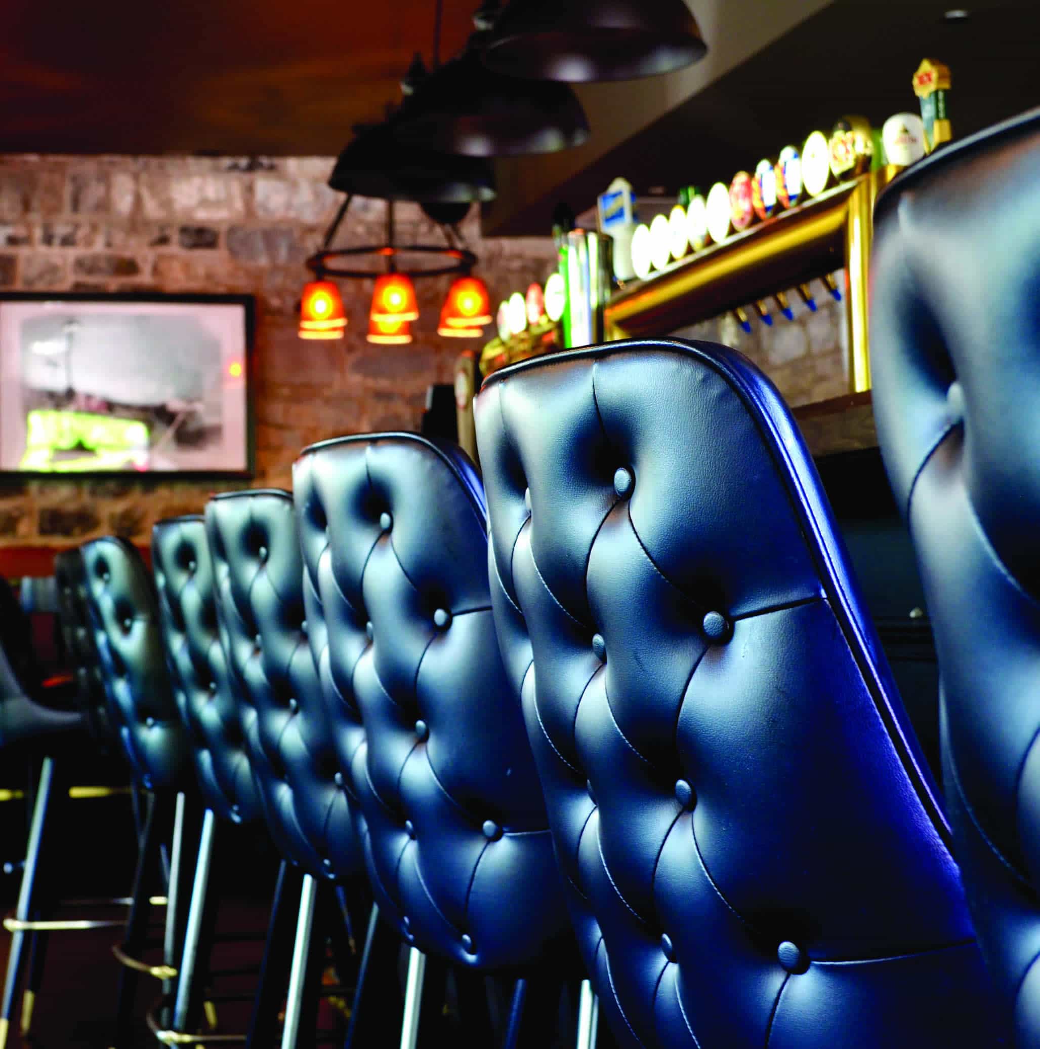 A row of tufted blue leather bar stools